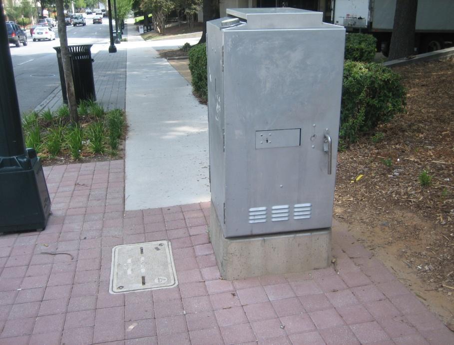 At the northeast corner of the intersection of 15 th and West Peachtree Streets, the traffic control cabinet is in the middle of the sidewalk, posing a major obstacle for pedestrians accessing the