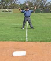 The base umpire will call a foul ball while facing the outfield. Note that the umpire straddles the foul line when facing the outfield.