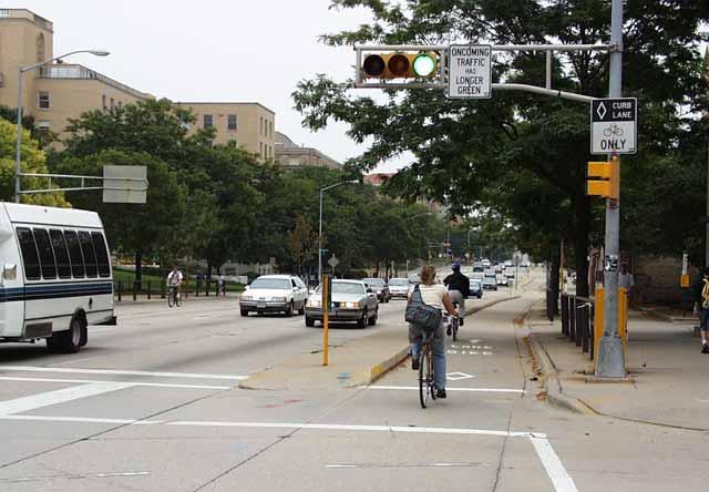 (This picture shows a bicyclist not wearing a helmet. FHWA strongly recommends that all bicyclists wear helmets.) Figure 15-21. Photo. Contraflow bike lane with bicycle-specific signal in Madison, WI.
