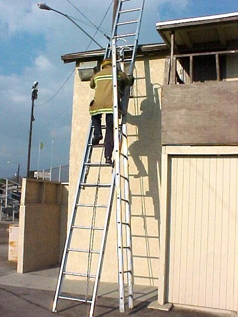 Remove roof ladder from shoulder, extend ladder toward ridge of roof by sliding ladder up roof on its beam,