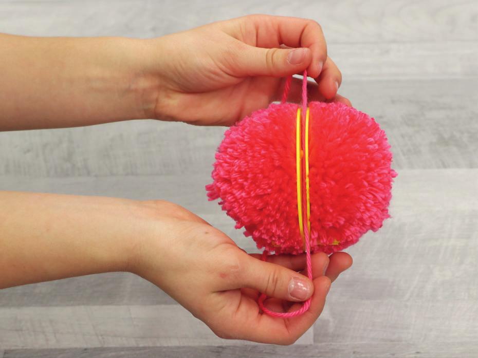 Cutting the pom-pom threads You will now need a single wool thread about 30 cm long in order to finish the pom-pom.