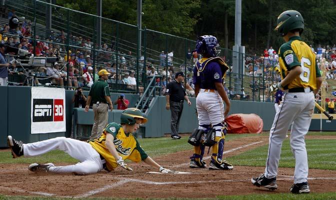 A player slides past the catcher to score a run in the baseball Little League World Series in Williamsport, Pennsylvania, in 2013. barrier (n.